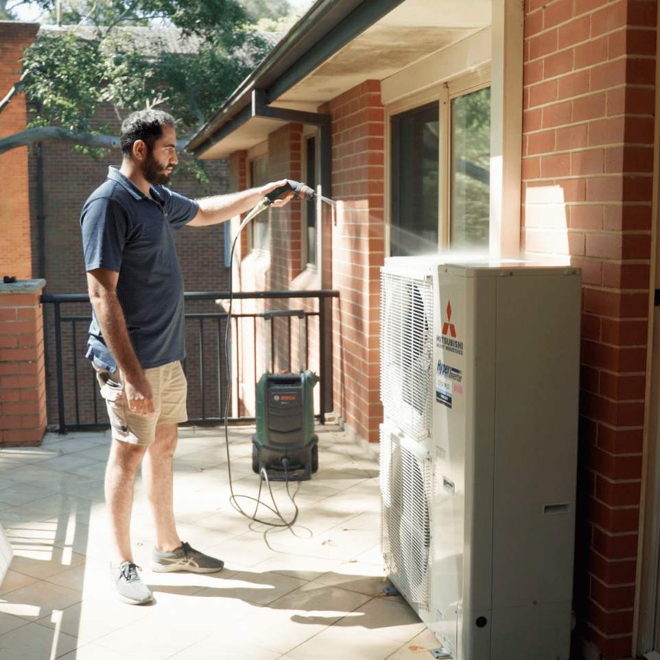 Technician cleaning an outdoor condenser unit